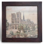 Tapeçaria decorativa representando vista da Catedral de Notre-Dame de Paris, em rica composição arquitetônica e paisagística, protegida por moldura de madeira escura. Mede 29x29cm.