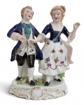 Grupo escultórico em porcelana Vieira de Castro, representando casal em trajes de época, com decoração policromada e detalhes dourados em relevo. Base ornamentada e marca da manufatura Vieira de Castro  Rio na parte inferior. Discreto sinal de restauro em uma das mãos. Em bom estado de conservação. Medidas: 19  14 cm.