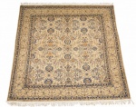 Tapete oriental estilo persa Kashan, de trama e densa espessura, decorado com rica composição floral em tons de marfim, bege e azul. Bordaduras elaboradas e franjas nas extremidades. Medidas: 2,57 x 2,65 m. Apresenta sinais de uso compatíveis com a antiguidade.