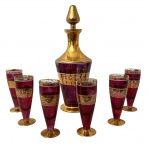 VENEZA - Conjunto para licor em cristal veneziano, composto por licoreira com tampa e seis cálices. Em tom rubi com rica decoração dourada, padrão clássico de inspiração Murano. Peças elegantes, com sinais do tempo no douramento. Medida da licoreira 30 cm.