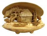 Escultura oriental em resina, trabalho minucioso com cena rural chinesa em alto-relevo: habitação tradicional, personagens, árvore, embarcação e roda dágua, esculpidos no interior da concha. Tampa externa ricamente trabalhada com paisagem oriental, pagode, ponte e montanha. Peça decorativa de grande delicadeza, típica do artesanato asiático do século XX. Mede 8cm x 6cm.