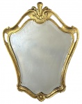 Espelho de parede em madeira entalhada e dourada, de inspiração rococó, com moldura recortada e rica decoração de volutas e concheados. Espelho de época com sinais naturais de uso e oxidação do mercúrio, conferindo charme e autenticidade à peça. Apresenta desgastes e restauros compatíveis com a idade. Mede 71cm x 55cm.