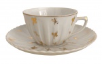 REAL - Xícara para chá com pires em porcelana Real, São Paulo, decoração em relevo com delicados motivos florais e filetes dourados. Peça de elegante acabamento, marcada na base. Apresenta sinais compatíveis com o uso e o tempo.