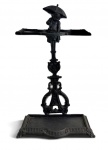 Bengaleiro antigo em metal patinado, ricamente ornamentado, com figura de putto segurando guarda-chuva no topo e estrutura superior para apoio de bengalas/guarda-chuvas, base com bandeja coletora. Peça de forte apelo decorativo, provável origem europeia, início do século XX. Mede 65 x 40 cm.