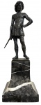 Escultura em metal patinado representando jovem espadachim, sobre elegante base em mármore Carrara. Trabalho de inspiração clássica, com rica modelagem das vestes e da anatomia, apresentando pátina escura compatível com o tempo. Peça decorativa de expressiva presença. Mede 25cm.