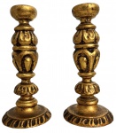 Par de castiçais em madeira entalhada e dourada, de inspiração barroca, com fuste torneado e base circular decorada. Produção peruana, conforme etiqueta na base (Hand Made in Peru). Peças decorativas em bom estado de conservação. Mede 20cm
