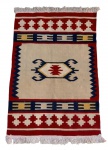 Tapete de inspiração Navajo, confeccionado em lã, com decoração geométrica policromada em tons de vermelho, azul, bege e ocre, acabamento com franjas nas extremidades. Em bom estado de conservação. Medidas: 98 x 157 cm.