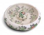 Floreira (jardineira) em porcelana Weiss, composta por recipiente circular e suporte perfurado removível para arranjos florais (frog), decorada com delicados motivos florais policromados em tons de verde, cinza e vermelho. Peça marcada na base Weiss, com selo de importação da Casa Uruguaiana. Apresenta sinais compatíveis com a idade e pequeno fio de cabelo na borda. Medidas: 30 cm de diâmetro.