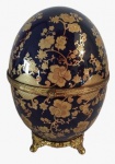 LIMOGES - Porta jóias em formato de ovo de porcelana com estrutura de ferro dourado e pintura artesanal com tema floral na tonalidade dourado. Medidas: Altura 22 cm e Diâmetro 15 cm.
