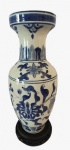 Vaso em porcelana branca com pintura na tonalidade azul, acompanha base em madeira. Medidas: Altura 35 cm e Diâmetro 15 cm. 