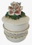 Potiche em porcelana na tonalidade branca com apliques em tema de flores. Medidas: Altura 10 cm e Diâmetro 7 cm.