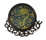 Prato decorativo chinês em porcelana na tonalidade azul e amarelo com tema dragão imperial, montado em um suporte de madeira entalhada. Obs. Necessita de restauro na madeira 
Medida: Diâmetro 25 cm. 