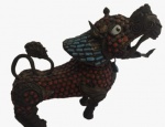 Escultura de cão de fó chinês antigo confeccionada em metal com incrustações de pedras que simulam coral na tonalidade vermelha e turquesa. Medida: altura 20 cm largura 10 cm comprimento 18 cm.