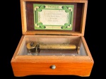 THORENS  SWITZERLAND. Antiga caixa de música mecânica suíça, modelo Nº 30, em caixa de madeira com tampa articulada e pequeno escudo em marchetaria no tampo. Interior com mecanismo musical de cilindro metálico e pente de lâminas, protegido por cobertura transparente, conservando etiqueta original Thorens Made in Switzerland. Executa quatro melodias: Tales of Vienna Woods, Blue Danube Waltz, La Paloma e Brahms Lullaby. O modelo Nº 30 é documentado com mecanismo de múltiplas melodias, incluindo versões com 52 lâminas. Medidas: 16,5 X 9,7 X 7,2 cm.