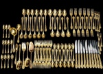 Faqueiro em metal dourado, composto por talheres para mesa, sobremesa, chá e café, além de peças para servir. Cabos ornamentados em relevo com motivos clássicos. Peças com marca de manufatura. Apresenta sinais compatíveis com o uso e o tempo.