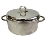 Elegante sopeira / panela de servir em metal espessurado a prata, com duas pegas laterais trabalhadas e articuladas, tampa abaulada com puxador ornamentado em forma de argola. Medidas: 15 x 29 x 21,5 cm.
