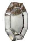ST JAMES. Antiga e imponente travessa em metal espessurado a prata, de formato oitavado alongado, com centro oval e larga aba facetada de linhas geométricas. Manufatura marcada St. James. Apresenta pequenos riscos e marcas de uso. Medidas: 49 x 32 cm.