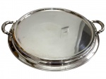 Antiga bandeja circular em metal espessurado a prata, com centro liso, borda moldurada e duas elegantes alças laterais trabalhadas em volutas. Apresenta marcas do tempo e de uso, com discretos riscos e pontos de desgaste no banho. Medidas:3 x 43,5 x 40 cm.