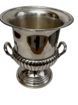 Antiga champanheira / balde de gelo em metal espessurado a prata, de formato circular, com corpo liso, duas alças laterais trabalhadas, faixa inferior canelada e base elevada com frisos decorativos. Medidas: 23 x 26 cm.