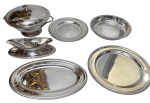 MERIDIONAL. Conjunto de baixela em aço inoxidável, composto por 6 peças, com acabamento polido e bordas decoradas por frisos perlados, sendo: duas bandejas redondas, uma bandeja oval, uma molheira com presentoir, uma saladeira e uma sopeira com tampa e alças laterais. Medidas: bandeja redonda grande: 29 x 1,5 cm; bandeja redonda média: 24,5 x 1,5 cm; bandeja oval: 34 x 22 x 1,5 cm; molheira: 25 x 12 x 7 cm; saladeira: 24,5 x 4 cm; sopeira: 28,5 x 24 x 17 cm.