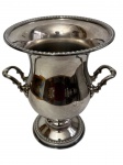 Antiga champanheira em metal espessurado a prata, de elegante feitio, corpo bojudo sobre base circular escalonada, com bordas ornamentadas por frisos em relevo e duas alças laterais decoradas com motivos vegetalistas. Medidas: 24,5 x 22 x 18 cm.