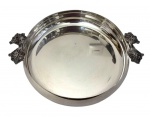 Wolff. Antiga centro de mesa em metal espessurado a prata, circular com borda elevada e escalonada, guarnecida por duas elegantes alças laterais fundidas e trabalhadas em relevo, representando folhagens estilizadas. Medidas: 7 cm de altura x 30,5 cm de diâmetro; 36 cm de largura total com as alças.