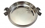 Wolff. Antiga centro de mesa em metal espessurado a prata, circular com borda elevada e escalonada, guarnecida por duas elegantes alças laterais fundidas e trabalhadas em relevo, representando folhagens estilizadas. Medidas: 7 cm de altura x 30,5 cm de diâmetro; 36 cm de largura total com as alças.
