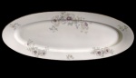 ROSENTHAL. Germany. Antiga e imponente travessa oval em porcelana alemã, de grandes dimensões, decorada com delicados arranjos florais em tons suaves de lilás, verde e cinza, distribuídos pela aba, com fino filete dourado na borda. Manufatura no verso. Medidas: 61 x 25 cm.