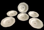 WOODS IVORY WARE, Inglaterra. Conjunto de 7 pratos fundos em faiança inglesa, esmaltado, com bordas levemente recortadas e filetadas a ouro, apresentando monograma decorativo ao centro. Marcados na base.  Medidas: 22 x 3 cm. Dois pratos apresentam marcas do tempo.