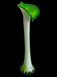 Antigo vaso solifluer em vidro artístico, de corpo alto e esguio, em vidro branco opalino com nuances em verde intenso, apresentando haste canelada, base alargada e recortada e boca assimétrica modelada em forma de cálice floral. Medidas: 41 x 9,5 cm.