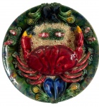Antigo prato decorativo de parede em faiança portuguesa, com rica decoração policromada em alto-relevo, representando caranguejo, mexilhões e outros elementos marinhos, sobre fundo de aspecto texturizado e borda em tons de verde. Peça de caráter decorativo, com suporte para suspensão no verso. Medidas: 6,5 cm de altura x 30 cm de diâmetro.