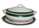 King China, Japão. Antiga sopeira em porcelana, acompanhada de travessa, decoração em faixa verde com delicados motivos dourados, filetes e detalhes em ouro. Corpo bojudo com alças laterais, tampa com puxador e abertura para concha. Marcada na base King China  Made in Japan. Medidas: sopeira 30 x 26 x 16 cm; travessa 32 x 22 x 3 cm.
