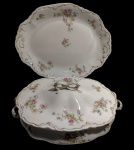JOHNSON BROS, Inglaterra. Antiga sopeira em porcelana, acompanhada de travessa de apresentação, com corpo e bordas recortadas, alças e puxador vazados. Decorada com delicados ramos florais policromados em tons de rosa e azul, com realces e filetes dourados. Manufatura no verso. Medidas: travessa 31,5 x 25 x 3 cm; sopeira 26,5 x 17 x 12,5 cm.