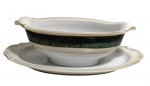 King China, Japan. Antiga molheira em porcelana com presentoir, decorada com larga faixa em verde profundo, ornamentada por delicados motivos florais dourados, contornada por frisos e bordas com detalhes em ouro. Corpo de formato oval com extremidades recortadas. Marcada na base. Medidas: 24 x 16,5 x 7 cm.