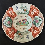 Excepcional e vibrante prato cerimonial de coleção com borda oitavada e levemente festonada, confeccionado em porcelana japonesa no estilo Imari / Família Rosa. Pintura e esmaltagem manual, apresentando ao centro uma reserva circular detalhada com figuras orientais em paisagem bucólica acompanhadas por borboletas e pequenos motivos florais, emoldurada por abas divididas em reservas com profusa ornamentação em tom rouge de fer (vermelho de ferro), crisântemos e peônias em rica policromia. Medidas: 3,5 cm de altura por 25 cm de diâmetro.
