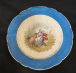 Prato de Coleção em Porcelana Francesa de formato circular com bordas festonadas, confeccionado em fina porcelana francesa no estilo Sèvres, aba ricamente esmaltada em vívido tom azul-celeste, contornando cavidade central com refinada cena galante de inspiração rococó retratando figuras nobres e pequeno cupido alado em paisagem bucólica, emoldurada por delicada guirlanda de filigranas douradas. Medida: 25 cm de diâmetro.