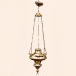Imponente Lampadário Sacro em bronze. Corpo abaulado com elementos fitomorfos e três anjos ao redor do bojo, correntes recortadas em arabescos. Med 1,22 m altura total.