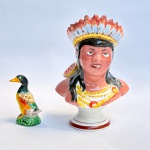 Dois paliteiros de coleção em porcelana com rica policromia, um representando um marreco e outro um indígena (possui restauro no cocar). Med paliteiro 16 x 12 cm marreco 7,5 x 5 cm.