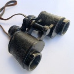 Nippon Kogaku Tokyo. Antigo binóculo japonês, modelo K.O.T., com campo de visão de 8,5, corpo em metal revestido em material preto texturizado, regulagem de foco e ajuste de dioptria. Acompanha estojo rígido e correia em couro. Apresenta desgastes, oxidação e marcas do tempo e do uso, especialmente no estojo e na correia. Funcionamento não testado.