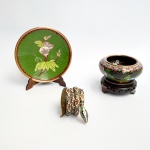 Lote com 3 decorativas miniaturas em cloisonné, sendo um prato, uma cobra e um cachepô com peanha. Med prato 10,5 cm, cobra 4 x 4 cm, vaso 6,5 x 8 cm.
