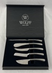 WOLFF. Jogo de facas para queijo em inox composto de 5 facas com diferentes formatos específicos para cada tipo de corte e consistência de queijo. Sem uso. Adquirido pela extinta loja de presentes Roberto Simões. Medindo: 27 cm e 20 cm, caixa: 5 x 25 x 31 cm.