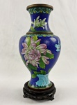 Vaso chinês em metal esmaltado de cloisonné, com fundo azul-cobalto e rica decoração policromada de flores, folhagens e motivos orientais. Acompanha peanha em madeira entalhada e vazada. Medidas: vaso: 23 cm de altura; peanha: 3 x 9,5 cm.
