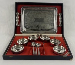 Conjunto de metal prateado, composto de: 6 taças para sorvete com colheres e bandeja com alças com fundo cinzelado. Total: 7 peças. Desgastes. No estojo. Bandeja mede; 39 x 25 cm.