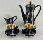 SLAVKOV. ARS BOHEMIA, Tchecoslováquia. Conjunto para café em porcelana esmaltada na cor preta, com decoração abstrata em branco e dourado, composto por: bule com tampa, leiteira e 2 xícaras com respectivos pires. Xícaras com interior dourado. Manufatura na base. O bule apresenta avarias, incluindo bicado no bico. Medidas: bule: 17 x 16 cm.