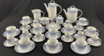 SCHMIDT BRASIL. Serviço de chá e café em porcelana branca esmaltada, com delicada decoração em azul e filetes dourados, composto por: bule de chá, bule de café, leiteira, cremeira, manteigueira, açucareiro, 10 xícaras de chá com respectivos pires e 10 xícaras de café com respectivos pires. Manufatura na base. Medindo: 20 x 23 x 12 cm, 26 x 21 x 10 cm, 12,5 x 15 x 8 cm, 5 x 17 x 10 cm, 11 x 9 cm, 8 x 16 cm.