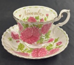 ROYAL ALBERT BONE CHINA, Inglaterra, série Flower of the Month, modelo Chrysanthemum, 1970. Xícara de chá de coleção com respectivo pires, em porcelana inglesa, ricamente decorada com crisântemos policromados, alusivos ao mês de novembro, bordas recortadas e filetes dourados. Manufatura no verso.