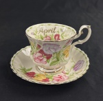 DON TON MANOR, Italy Design. Xícara de chá de coleção com respectivo pires, em porcelana branca esmaltada, com rica decoração policromada de flores em tons rosados, lilases e amarelos, folhagens verdes e inscrição April. Bordas recortadas e filetadas a ouro. Manufatura no verso.