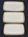 IVORY CHINA BY PORCELANA SCHMIDT BRASIL, Roberto Simões. Três travessas em porcelana marfim esmaltada, com faixa decorativa policromada de motivos florais e arabescos, emoldurada por largas bordas douradas. Manufatura e assinatura identificadas no verso. Medindo: 29 x 15,5 cm e 37,5 x 21 cm.