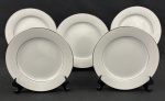 NORITAKE, Japão. Cinco pratos para sobremesa em porcelana japonesa modelo Buckinham, na cor branca com elegantes frisos prateados e desenhos florais leitosos. Medindo: 21 cm.