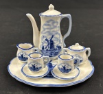 Delft, Holand. Mini tetê-a-tetê, em porcelana branca com flores e moinhos na cor azul cobalto. Composto de Bandeja (12 x 10cm), bule (8 x 7 cm), leiteira (2,5 x 3 cm), açucareiro (3 x 4 cm) e 2 xícaras com seus pires.